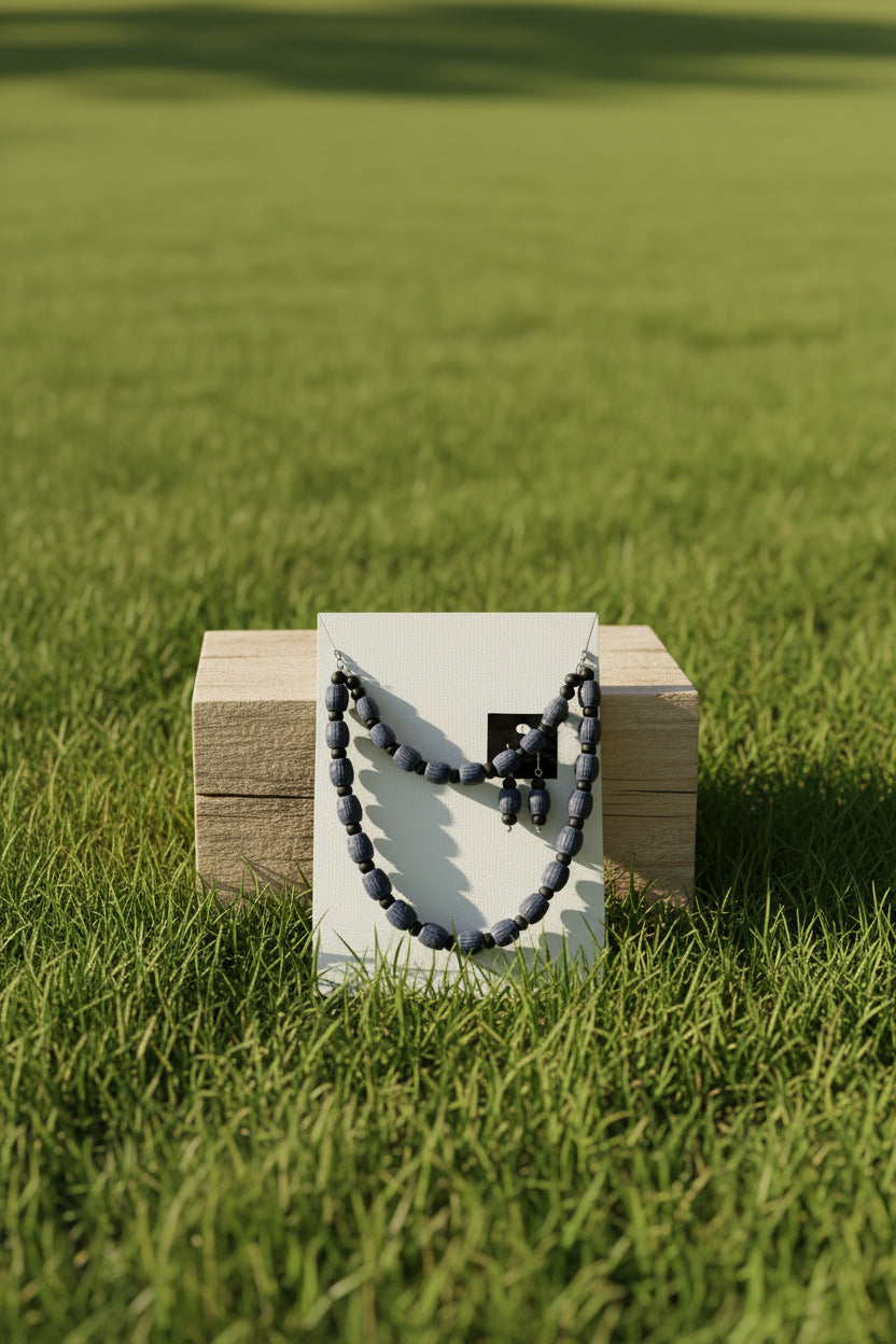 Navy blue carved barrel bead necklace and earring set on wood surface