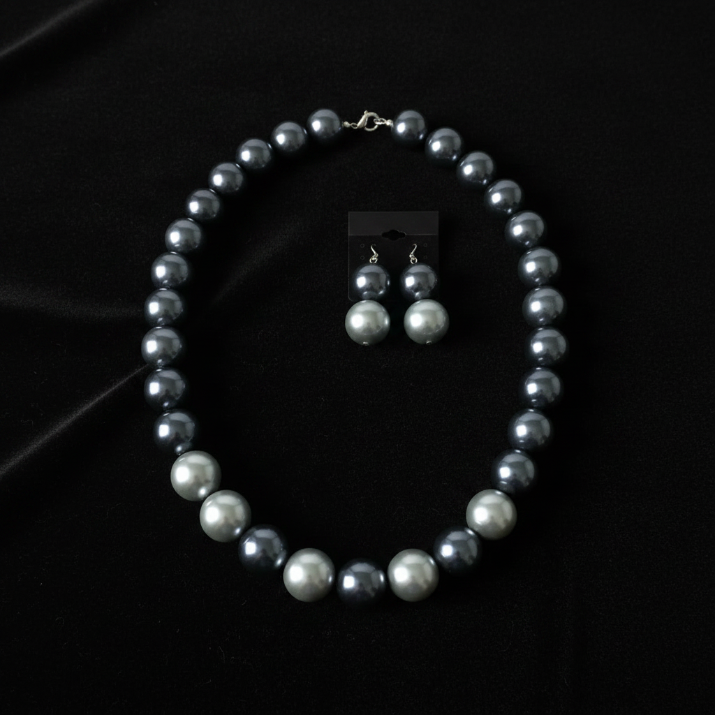 Gray silver pearl necklace set with matching earrings displayed on dark velvet