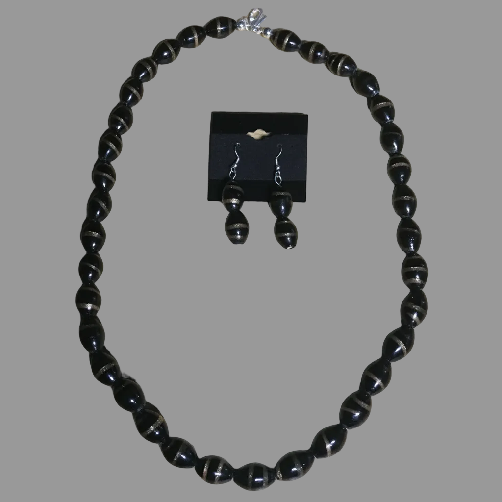 Black oval glass bead necklace set with gold swirl detail on brown wood surface