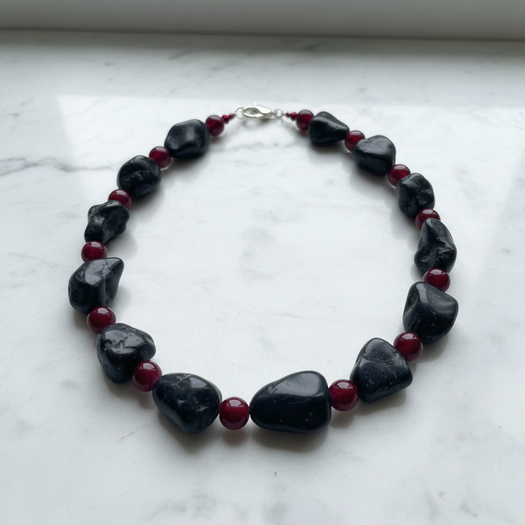 Black magnesite and burgundy glass necklace set on white marble