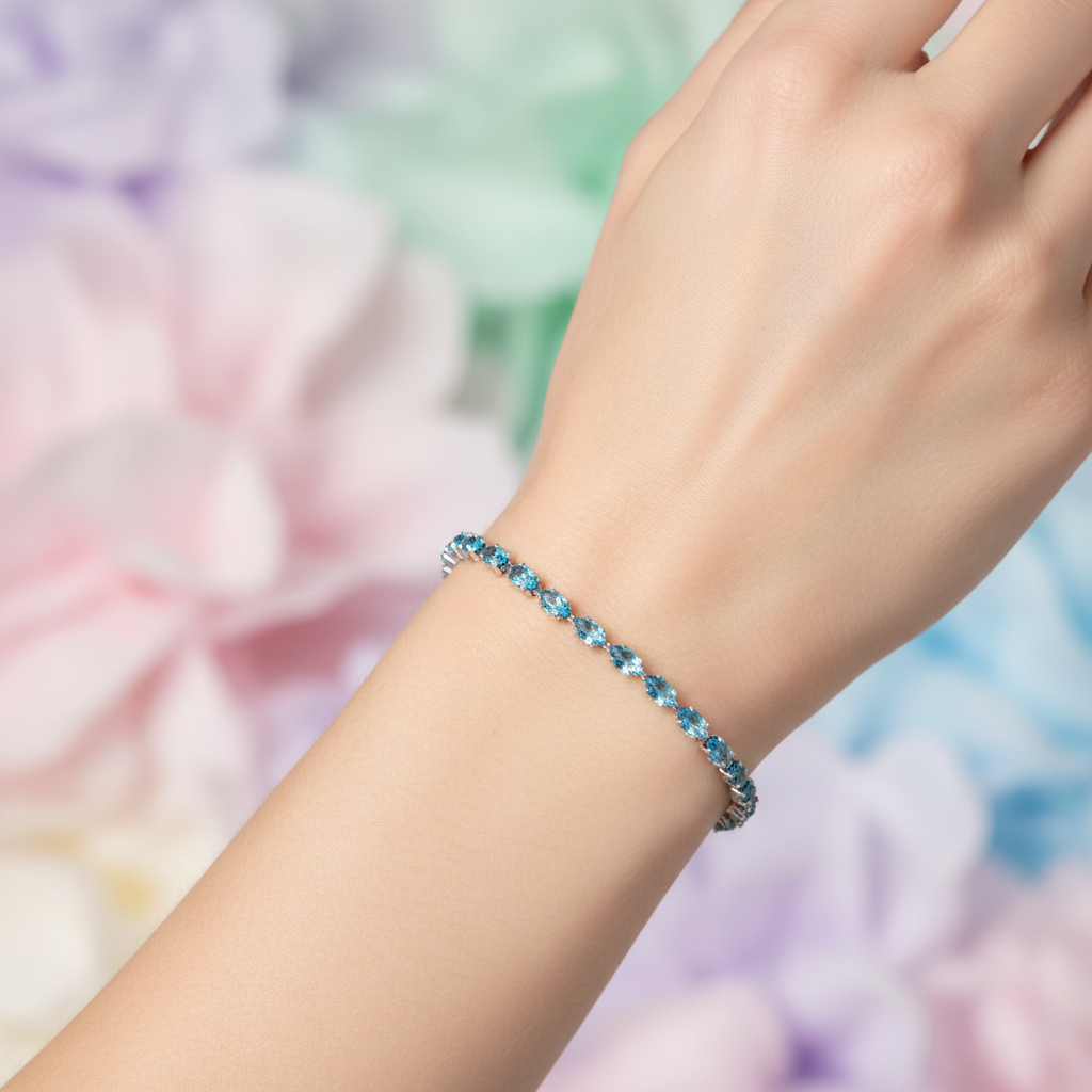 Blue topaz crystal tennis bracelet on model's wrist with light blurred background