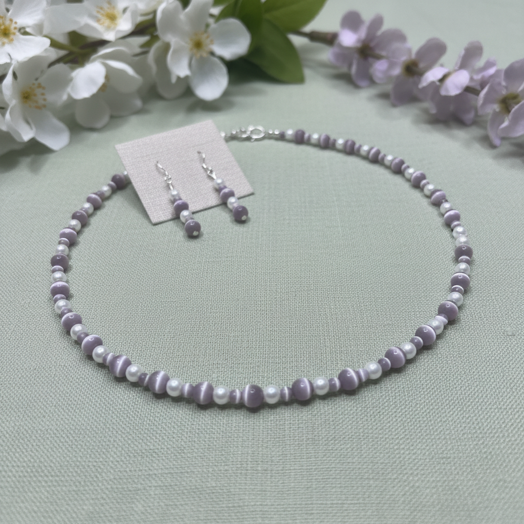Lilac cat's eye and pearl necklace set on sage green linen with spring florals