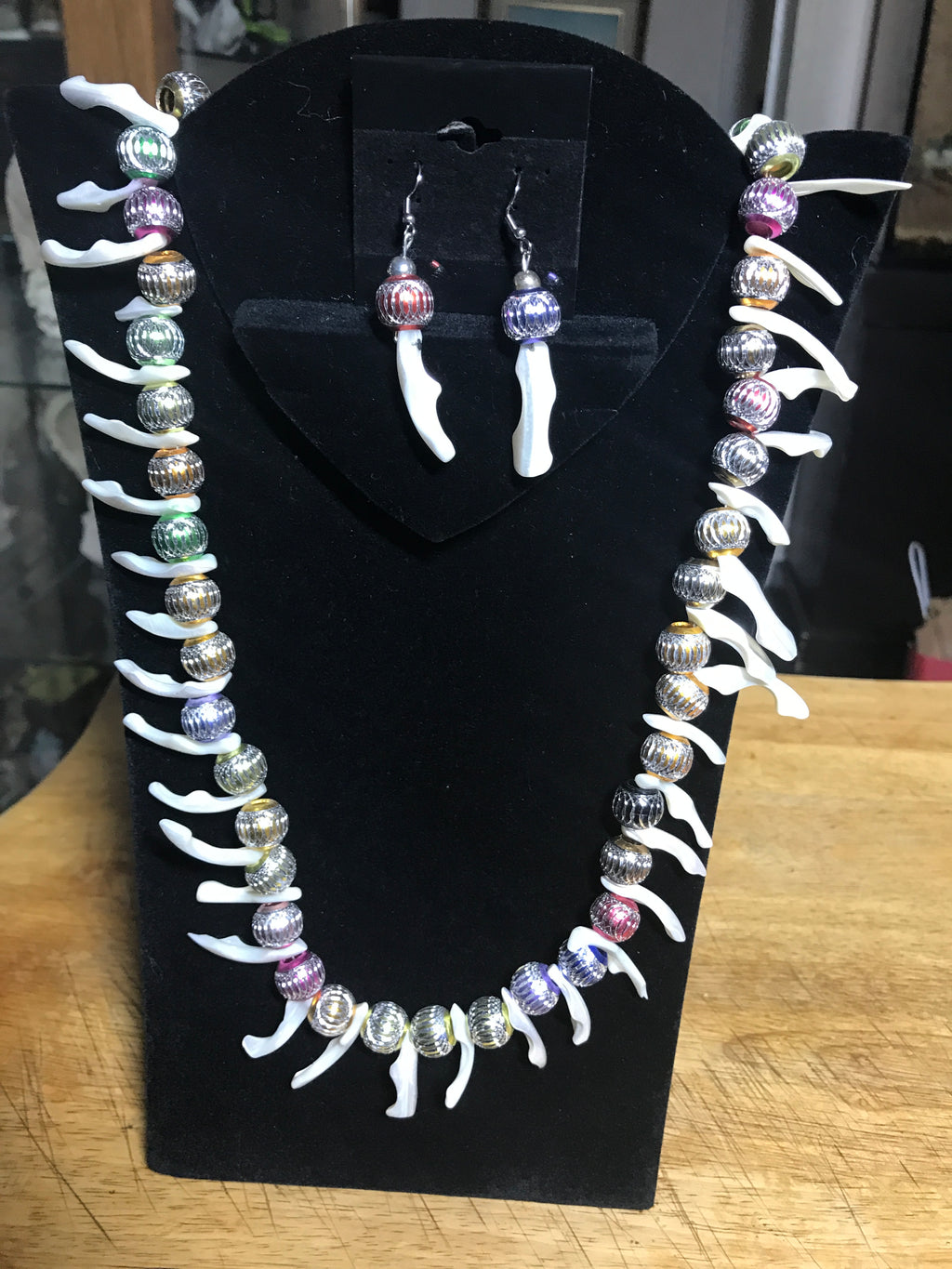 MOP shell and laser-etched aluminum beaded necklace and earring set on display stand