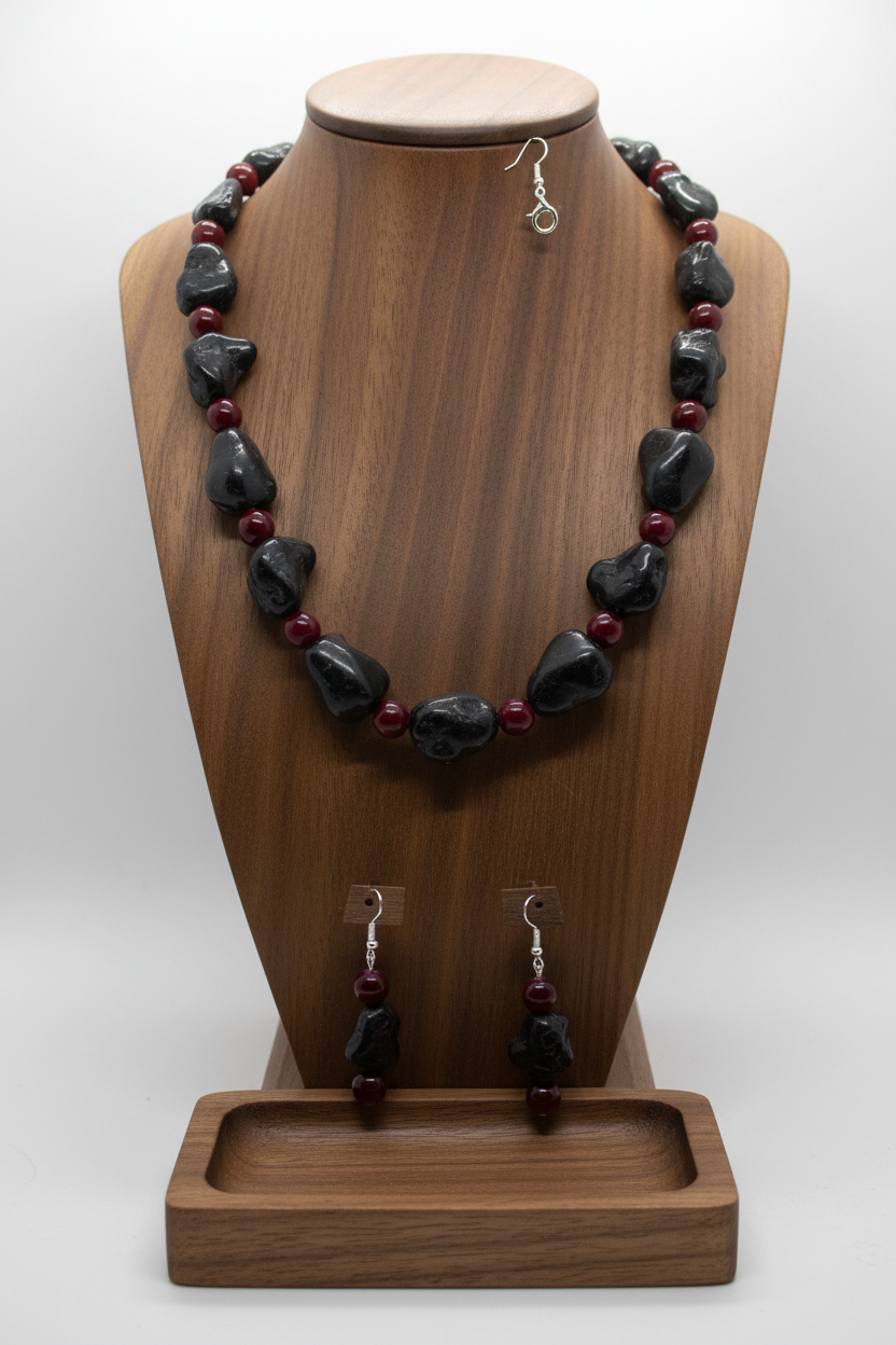 Black magnesite and burgundy glass necklace set displayed on wooden jewelry stand with neutral background
