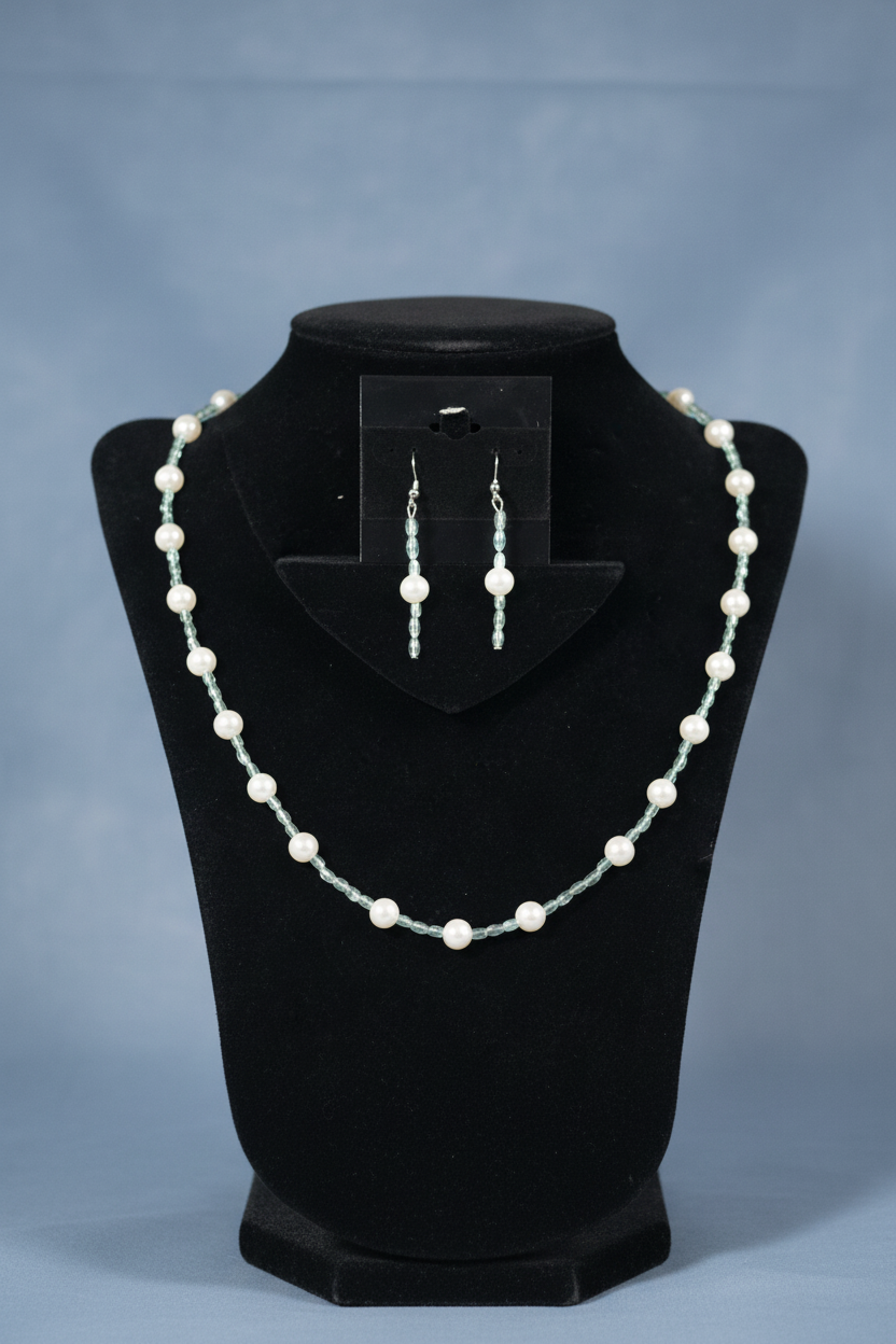Pearlescent blue oval and pearl necklace set on dusty blue backdrop